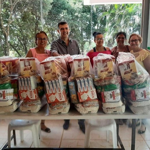 Voluntários do Instituto Reerguer ao lado de uma mesa com cestas básicas preparadas para entrega.