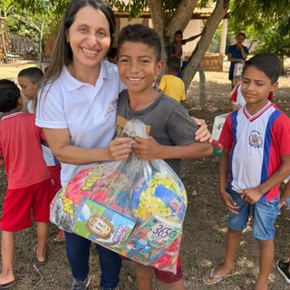 Voluntária do Instituto Reerguer abraça um menino que recebe uma sacola de presentes durante uma ação social.